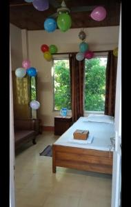 1 dormitorio con 1 cama con globos colgando del techo en Akarshan Bono Bunglow, en Lataguri