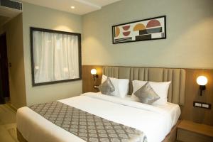 a bedroom with a large white bed and a window at Hotel Westend in Udaipur
