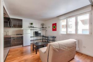 een woonkamer met een bank en een keuken bij Cosy studio à proximité du Parc Sergent Blandan in Lyon