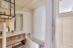 een badkamer met een wastafel en een spiegel bij Cosy studio à proximité du Parc Sergent Blandan in Lyon