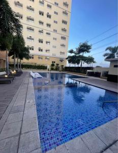 a swimming pool in front of a large building at Neat Unit in Holland Park Southwoods in Biñan