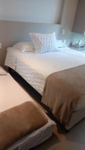 a bed with white sheets and pillows in a room at Rooftop 470 - Novíssimo Flat Boa Viagem in Recife