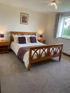 a bedroom with a large bed with two night stands and a window at Bungalow in Pillaton in Saltash