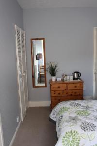 a bedroom with a bed and a dresser and a mirror at Beamsley Lodge B&B in Eastbourne