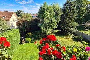 einen Garten mit roten Blumen und einem Haus in der Unterkunft 3 room apartment, 90 sqm, quiet, 25 min from Paris in Le Vésinet