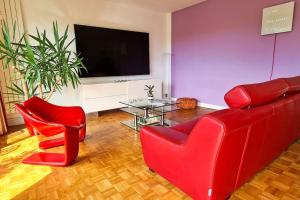 a living room with red chairs and a flat screen tv at Casalionel Le calme à 25 min de Paris in Le Vésinet