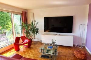 ein Wohnzimmer mit einem Flachbild-TV und roten Stühlen in der Unterkunft 3 room apartment, 90 sqm, quiet, 25 min from Paris in Le Vésinet