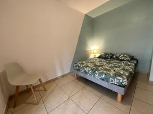 a small bedroom with a bed and a chair at Appartement T3 proche aéroport et Nordev in Sainte-Clotilde