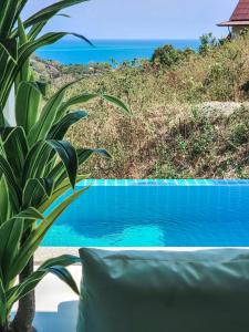 a swimming pool with a couch next to the ocean at BaanKuer Hill Pool Villa in Ko Lanta