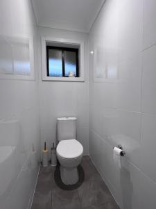 a white bathroom with a toilet and a window at Kangaroo Island Homestays in Kingscote