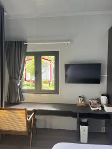 Pokój z biurkiem, telewizorem i oknem w obiekcie NAI Homestay w mieście Ben Tre