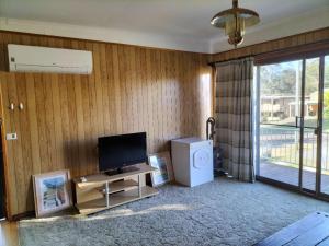 a living room with a television and a table at Surfside two-bedroom holiday upstairs in Batemans Bay