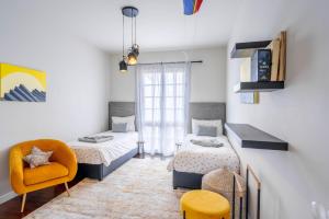 1 dormitorio con 2 camas y silla amarilla en VILLA LEONARDO, en Caniço