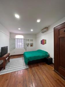 Schlafzimmer mit einem grünen Bett und Holzboden in der Unterkunft CASA MORENO se paga en USD o Dolar Blue! No se confunda in Buenos Aires