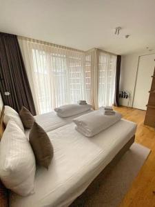 a large white bed in a room with windows at Luxury Mountain Hotel Apartment in Andermatt