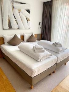 a bedroom with two beds with white pillows on them at Luxury Mountain Hotel Apartment in Andermatt