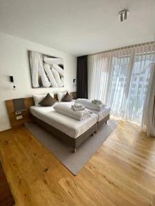 a bedroom with two beds and a large window at Luxury Mountain Hotel Apartment in Andermatt