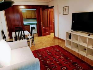 Il comprend un salon doté d'un canapé blanc et d'une télévision à écran plat. dans l'établissement Apartamento Entre Estaciones, à Oviedo