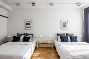 Duas camas num quarto com paredes brancas e almofadas azuis em Elegant City Home em Helsinque