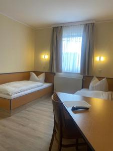 a hotel room with two beds and a table at REGIOHOTEL Salzland Schönebeck 