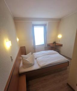 een slaapkamer met een bed met witte lakens en een raam bij REGIOHOTEL Salzland Schönebeck 