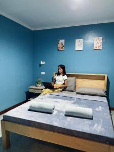a woman sitting on a bed with a laptop at MUBA HOSTEL in Moalboal