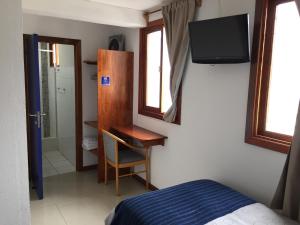 a bedroom with a bed and a television on the wall at Hotel Esmeralda in Iquique