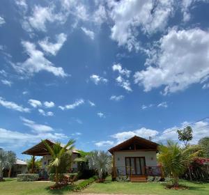 a house with palm trees and a blue sky at Recanto da Barra Chalé in Barra Grande