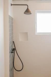 a shower with a hose in a bathroom with a window at Villa da Comporta - Quarto Praia da Comporta T0 in Comporta