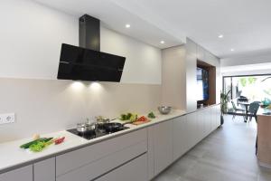 a kitchen with white cabinets and a flat screen tv on the wall at Duplex Los Tinos II 32 by VillaGranCanaria in Maspalomas