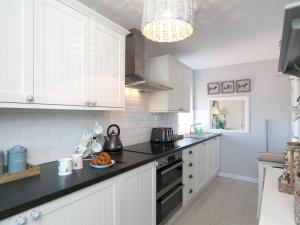 a kitchen with white cabinets and a black counter top at Pass the Keys Beautiful 3 bedroom apartment with Pool Access in Trearddur