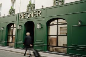 パリにあるHôtel Riesnerの路上のレジエール店を通り過ぎて歩く女
