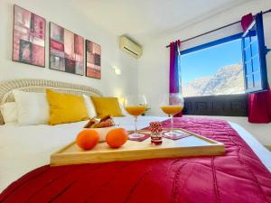 een dienblad met twee glazen wijn en sinaasappels op een bed bij Seaview Townhouse in Puerto Santiago & Los Gigantes in Puerto de Santiago