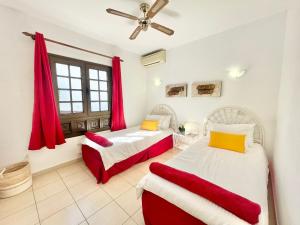 two beds in a room with red curtains at Seaview Townhouse in Puerto Santiago & Los Gigantes in Puerto de Santiago