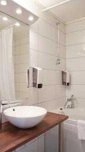 a bathroom with a white sink and a tub at Havila Hotel Geiranger in Geiranger +37 photos