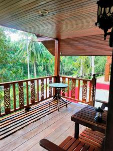 a wooden porch with a table and a bench on it at Family Resort in Baan Tai