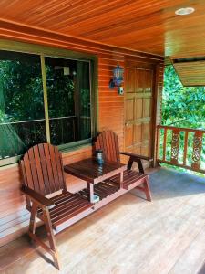 two chairs and a wooden table on the porch of a cabin at Family Resort in Ban Tai