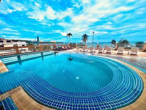 einen Pool mit Stühlen und das Meer im Hintergrund in der Unterkunft AA Hotel Pattaya in Pattaya