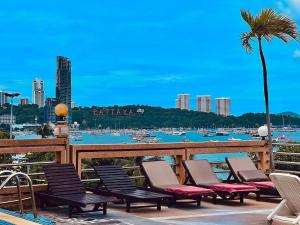 eine Gruppe von Stühlen und ein Strand mit einer Palme in der Unterkunft AA Hotel Pattaya in Pattaya