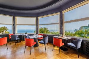 a restaurant with tables and chairs and large windows at Dormy House in Étretat