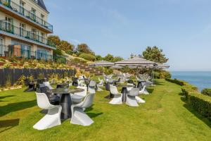a row of tables and chairs with the ocean in the background at Dormy House in Étretat
