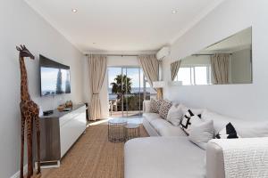 sala de estar con sofá blanco y TV en Stunning Sea View Apartment - Camps Bay, en Ciudad del Cabo