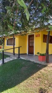 ein gelbes Gebäude mit einer Holztür im Hof in der Unterkunft Cabañas La Soñada in Chajarí