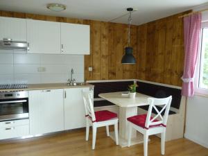 a kitchen with white cabinets and a table and chairs at De Jutter Edelweiss in Gosau