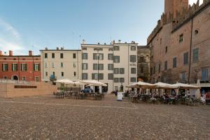 eine Gruppe von Tischen und Sonnenschirmen in einem Innenhof mit Gebäuden in der Unterkunft Hotel dei Gonzaga in Mantua