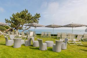 a group of chairs and umbrellas on the grass at Dormy House in Étretat