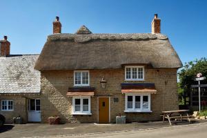 an old brick building with a thatched roof at Dusk at The Sun Inn Felmersham in Sharnbrook