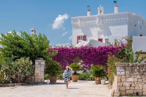 a woman standing in front of a garden with purple flowers at Masseria Torre Coccaro in Savelletri di Fasano