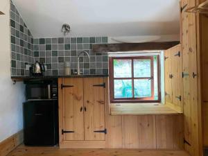 eine Küche mit Holzschränken und einem Fenster in der Unterkunft The Nest at the Pink Cottage in Carmarthen