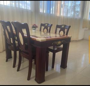 een houten tafel met vier stoelen en een tafel en een tafel en stoelen bij Lux Suites Mkomani Beachfront Apartment in Mombasa
